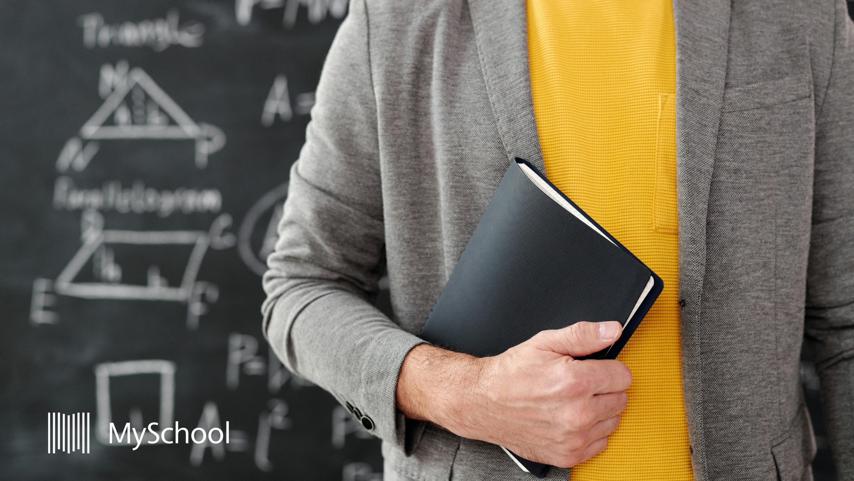 Teacher holding planner in classroom with academic formulas