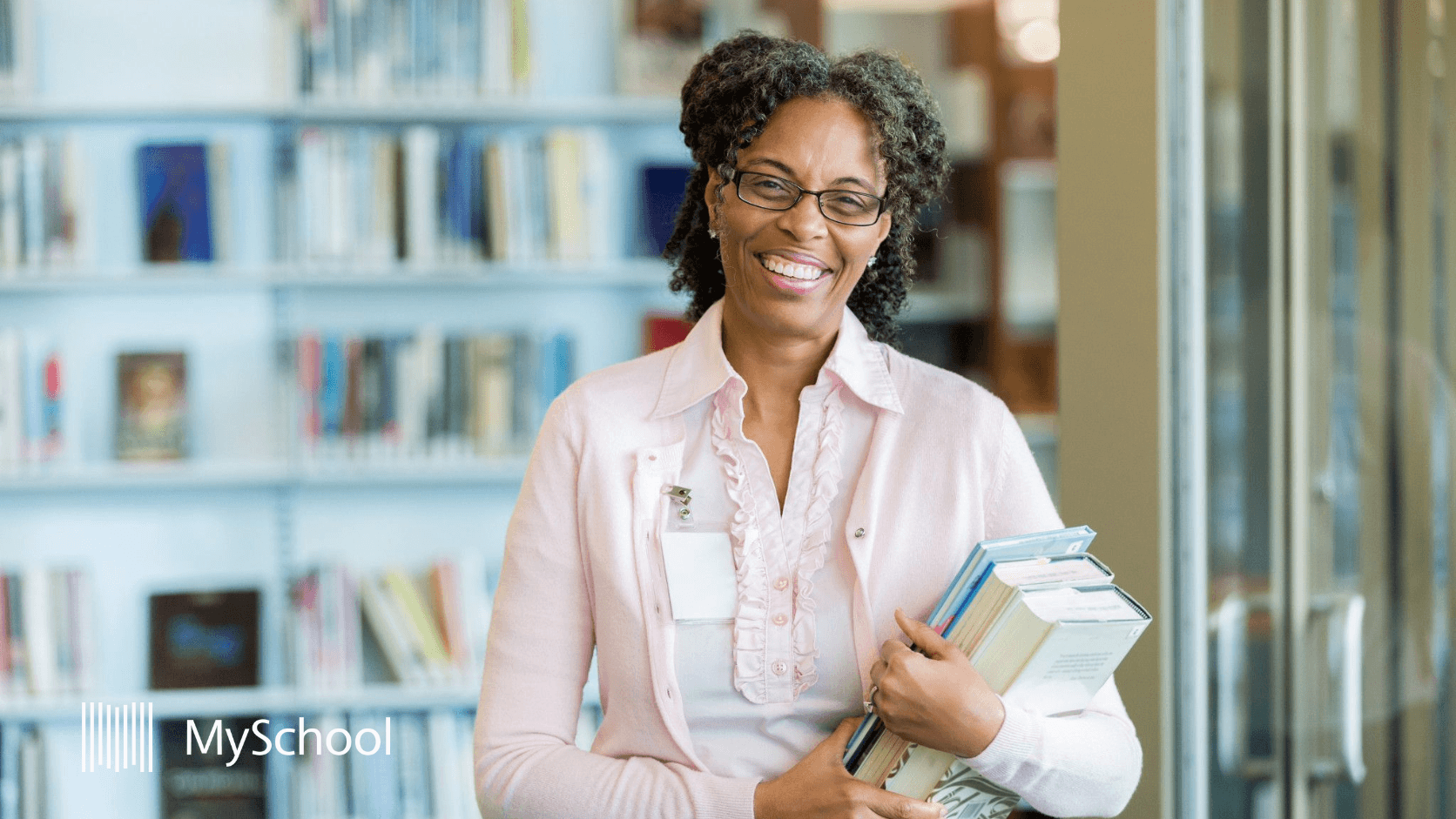 School staff member in library holding educational materials
