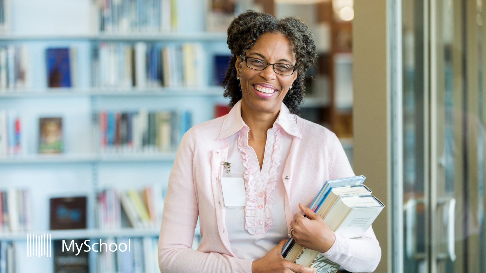 School staff member in library holding educational materials