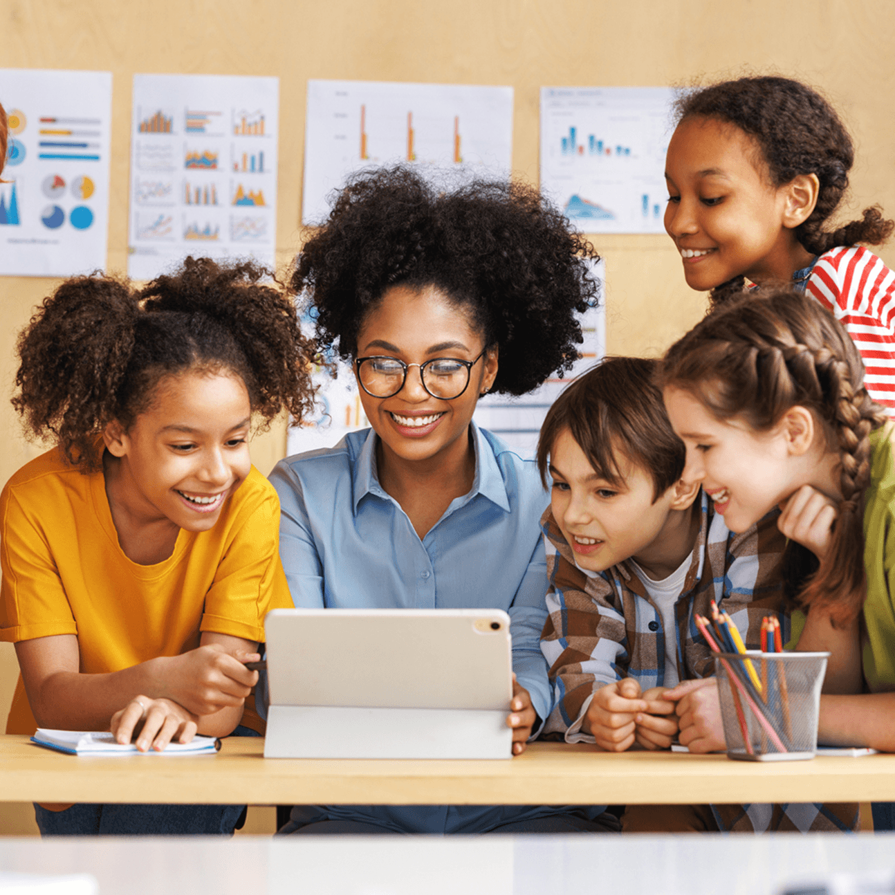 Teacher and students gathered around a tablet during a classroom learning activity