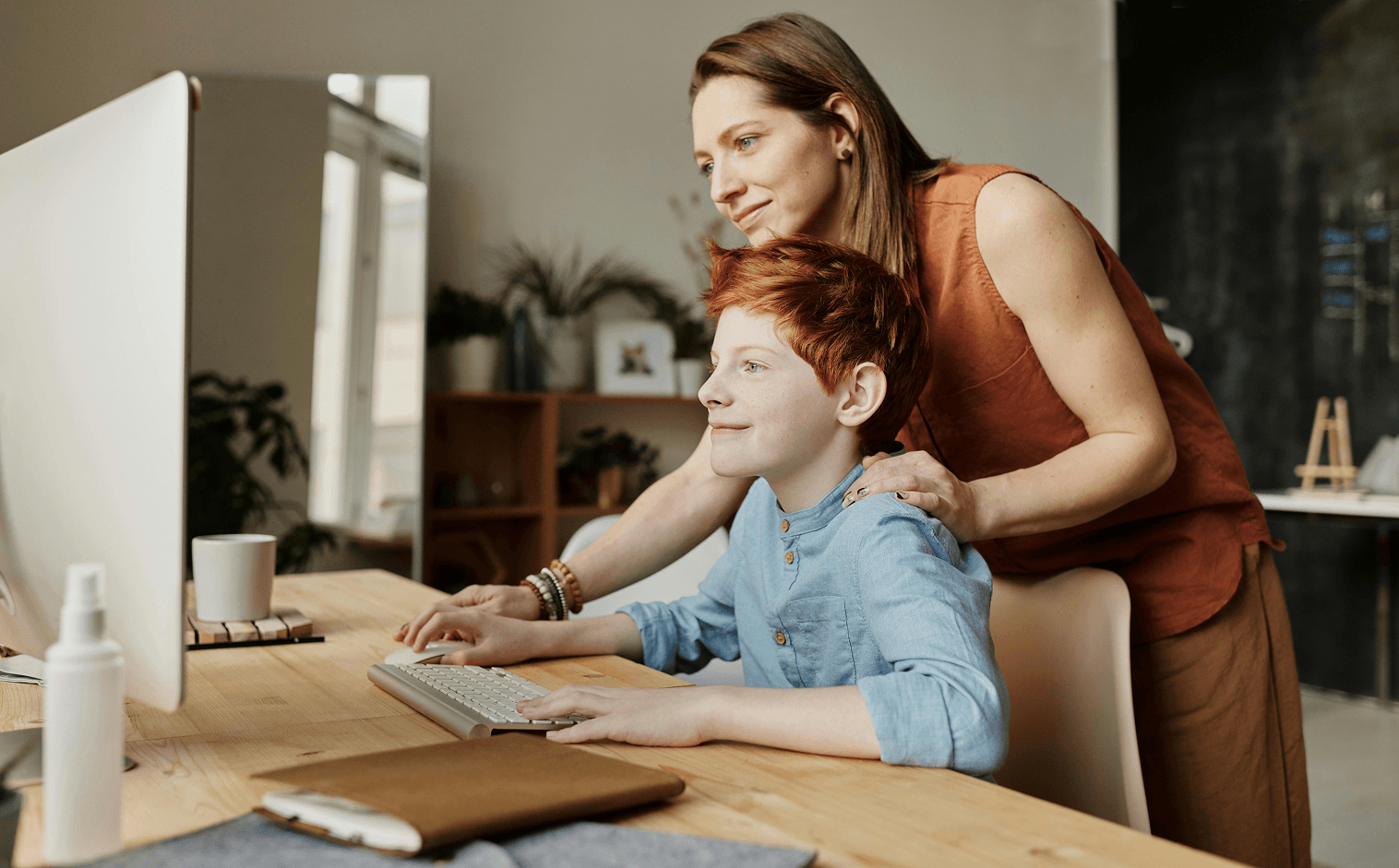 Mother and son at home checking MySchool's family portal to view student information on desktop computer