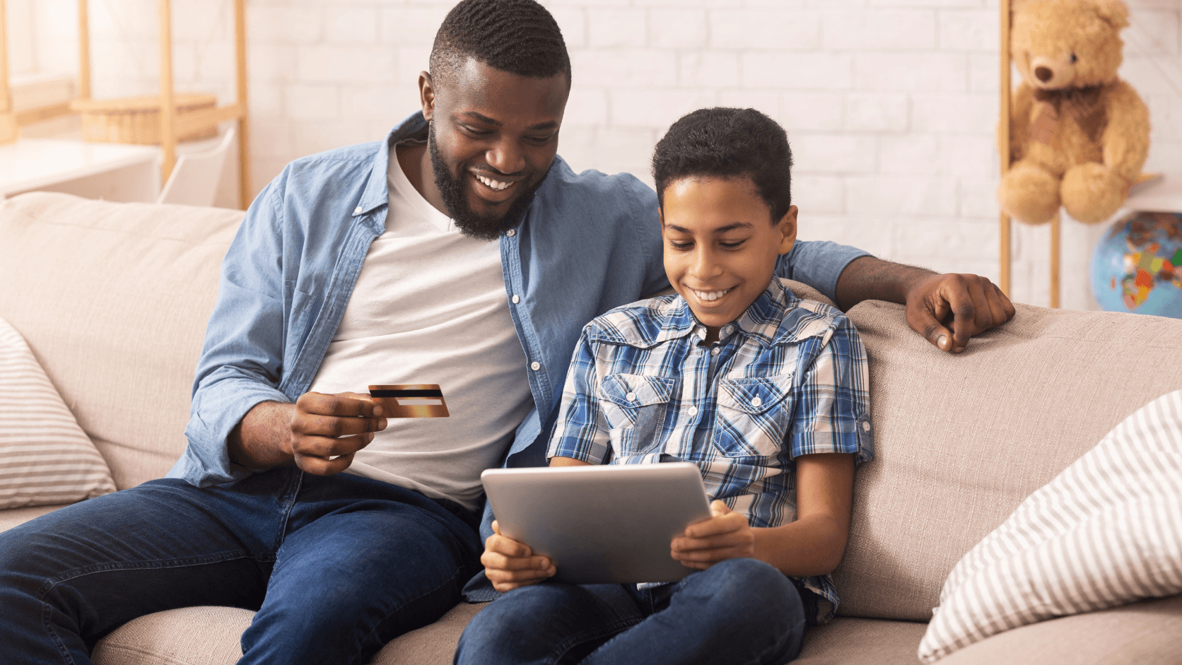 Father and son on couch completing tuition payment using MySchool's payment system on tablet