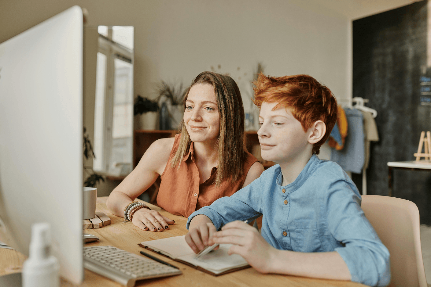 Parent with a child looking at computer screen together at home, checking school information